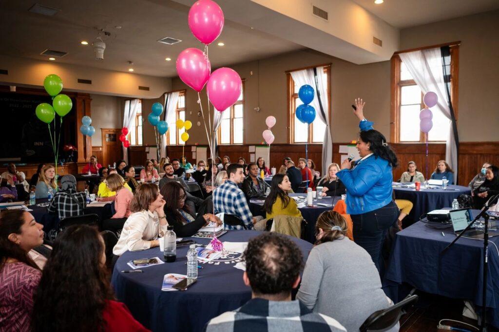 A full room of participants, balloons overhead, at a live session led by Crystal D’Cunha